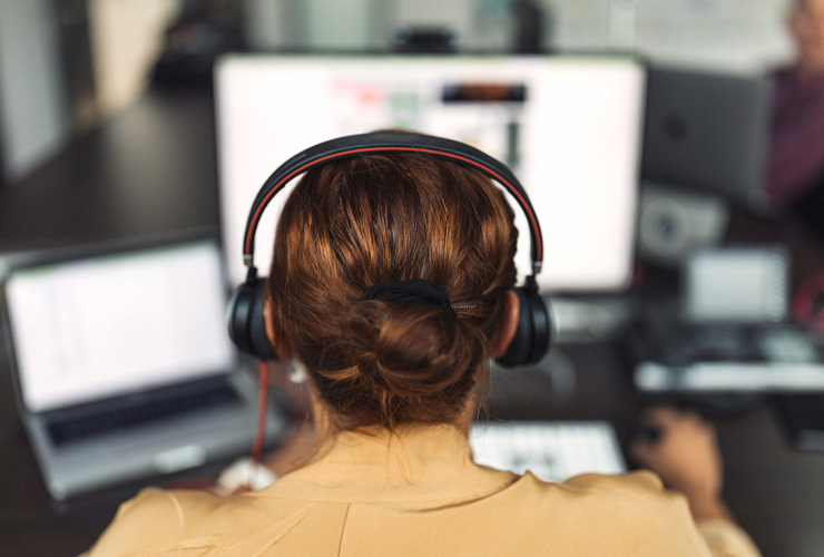 Person mit Kopfhörern arbeitet an einem Computer.